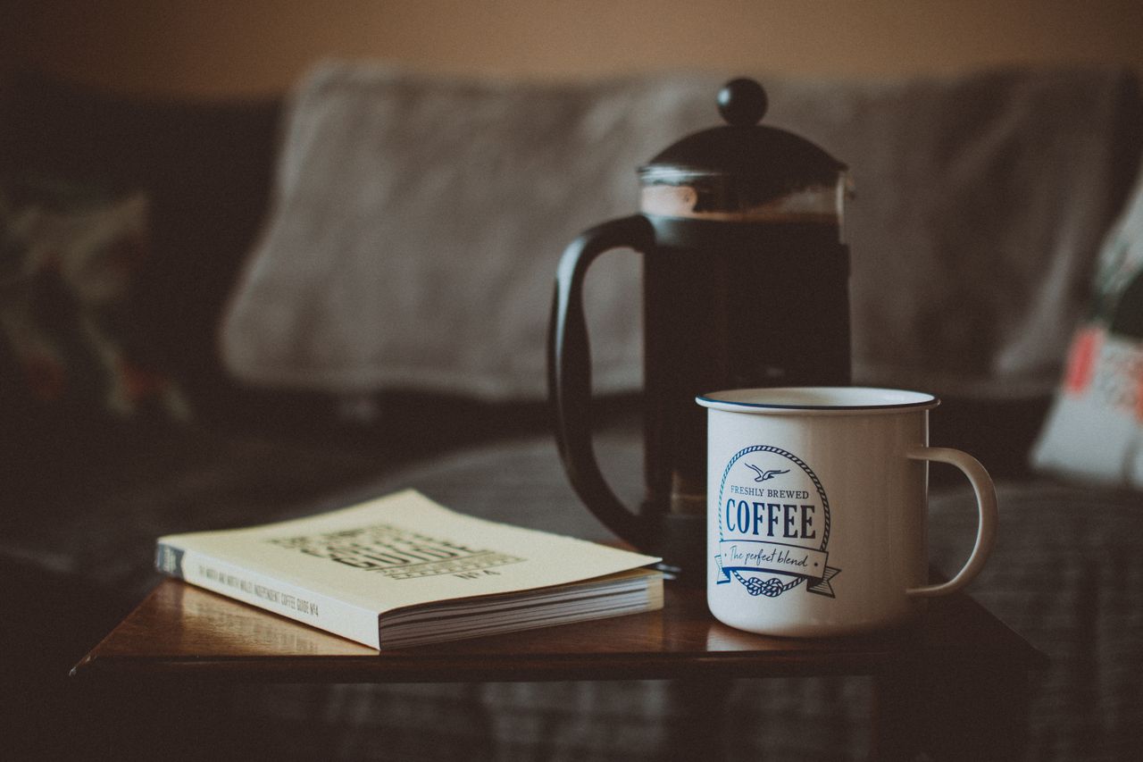 secangkir-kopi-buku-french-press-di-atas-meja