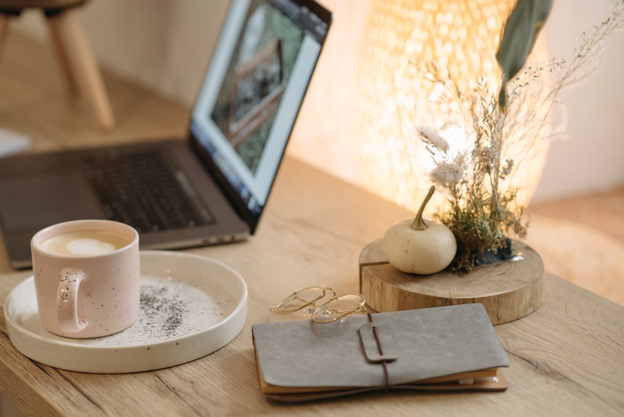 laptop-buku-catatan-dan-secangkir-kopi-di-atas-meja-dengan-hiasan-dekoreatif-bunga-kering