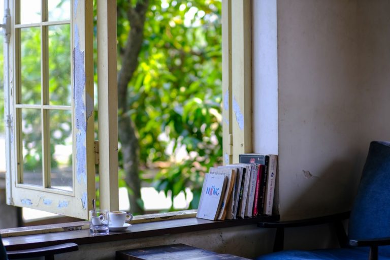 udut-tenang-di-kafe-Vietnam-dengan-buku-kursi-dan-jendela-terbuka-yang-menghadap-tanaman-hijau
